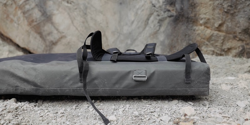 Crash pad with shoulder straps and durable outer shell placed on gravel