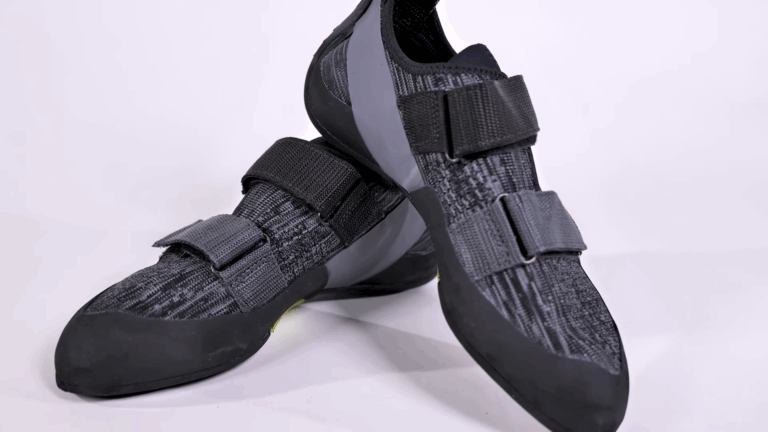 A pair of black bouldering shoes with velcro straps shown in a studio setting