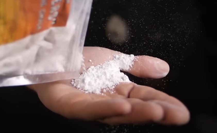 A bag of chalk is emptied onto a hand