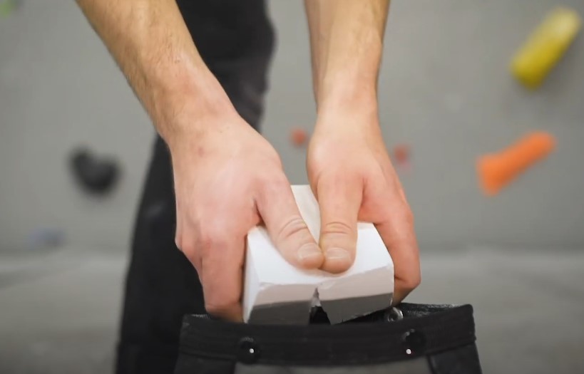 Hands carefully place chalk into a climbing bag